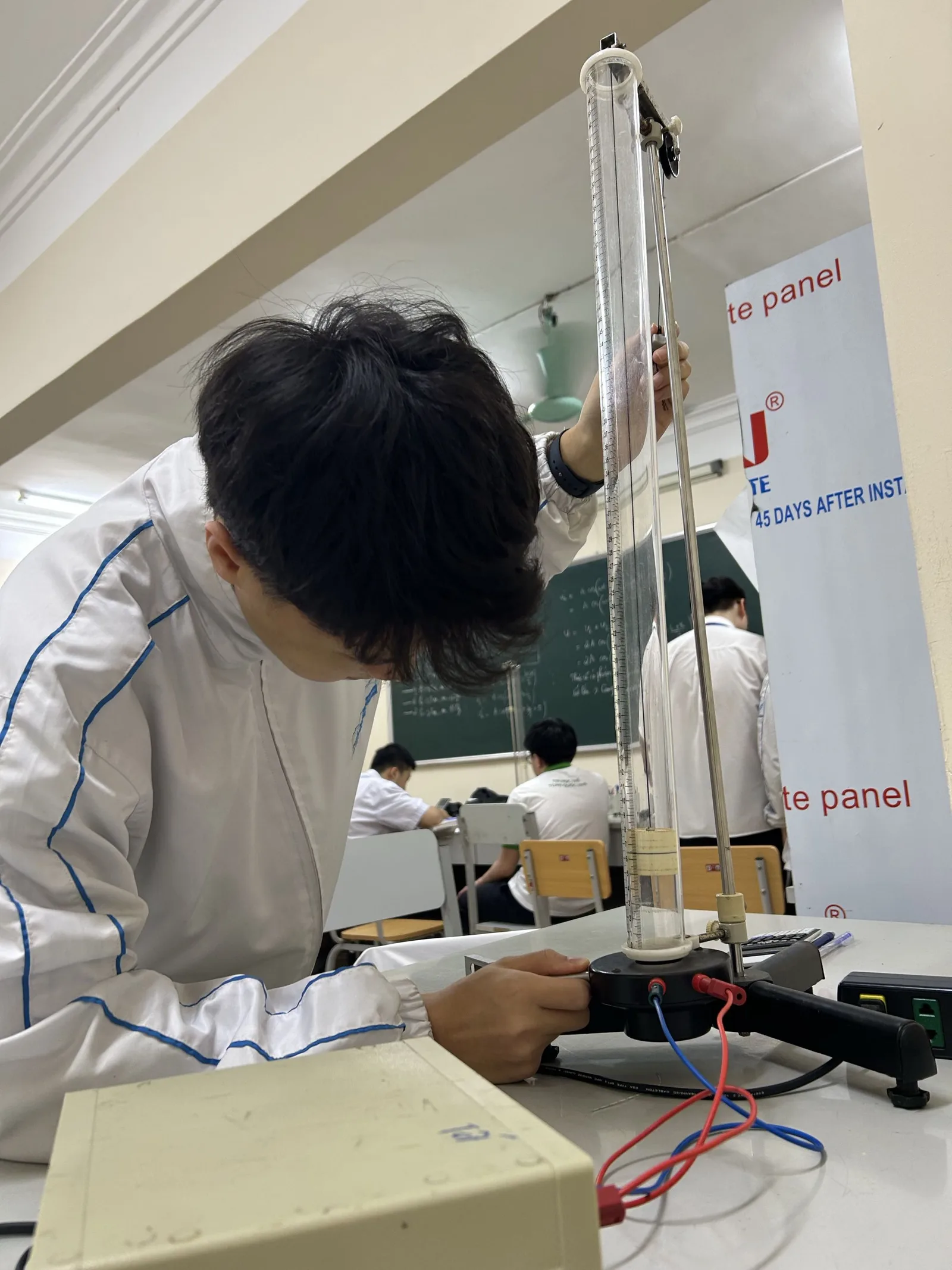 Nguyen Gia Tu in a white jacket adjusting laboratory apparatus
