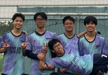 Football teammates in matching Arsenal jerseys posing together by a goal